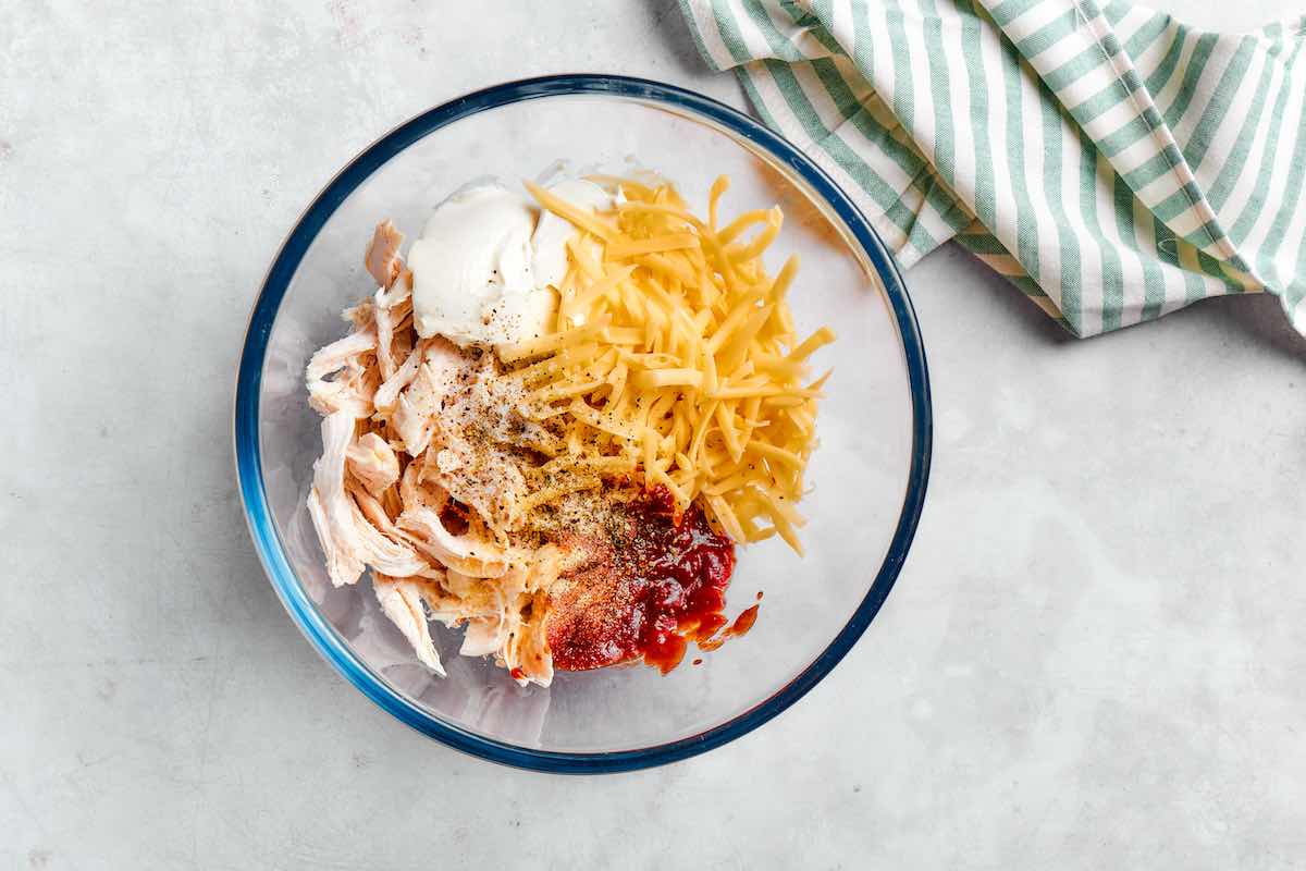 chicken, shredded cheese, sour cream, and salsa in a bowl.