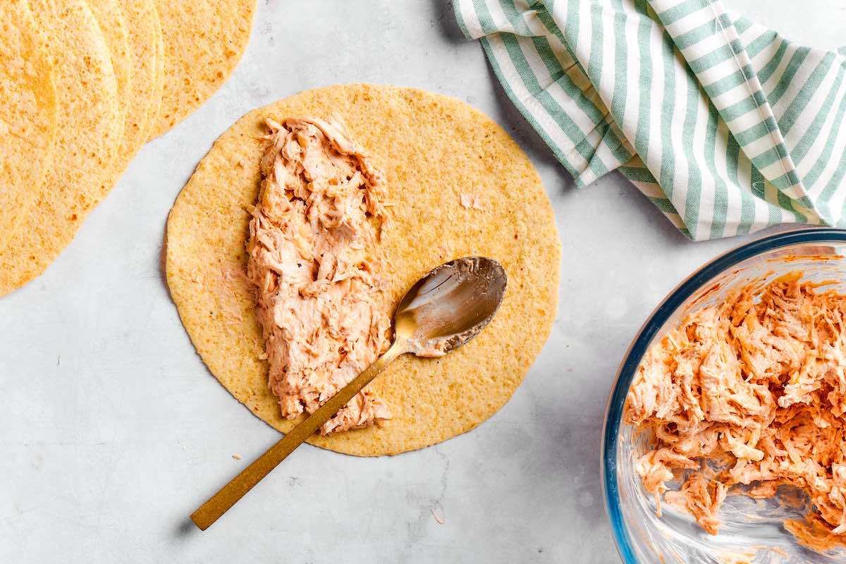 spreading chicken mixture on a tortilla.