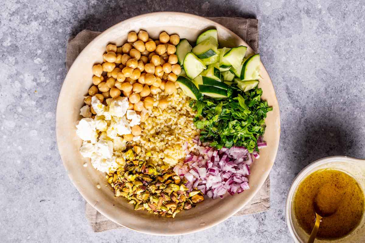 chickpeas, cucumbers, red onion, pistachios and feta in a bowl.