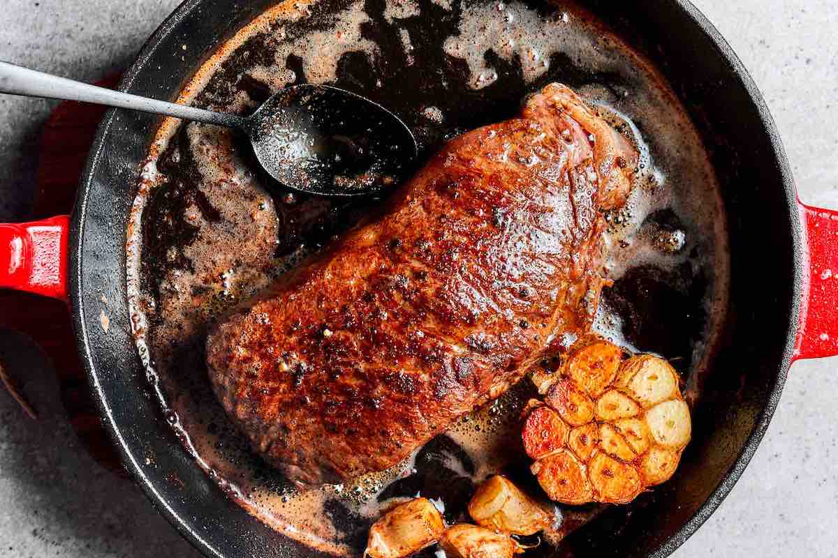 revere seared steak on a skillet with melted butter.