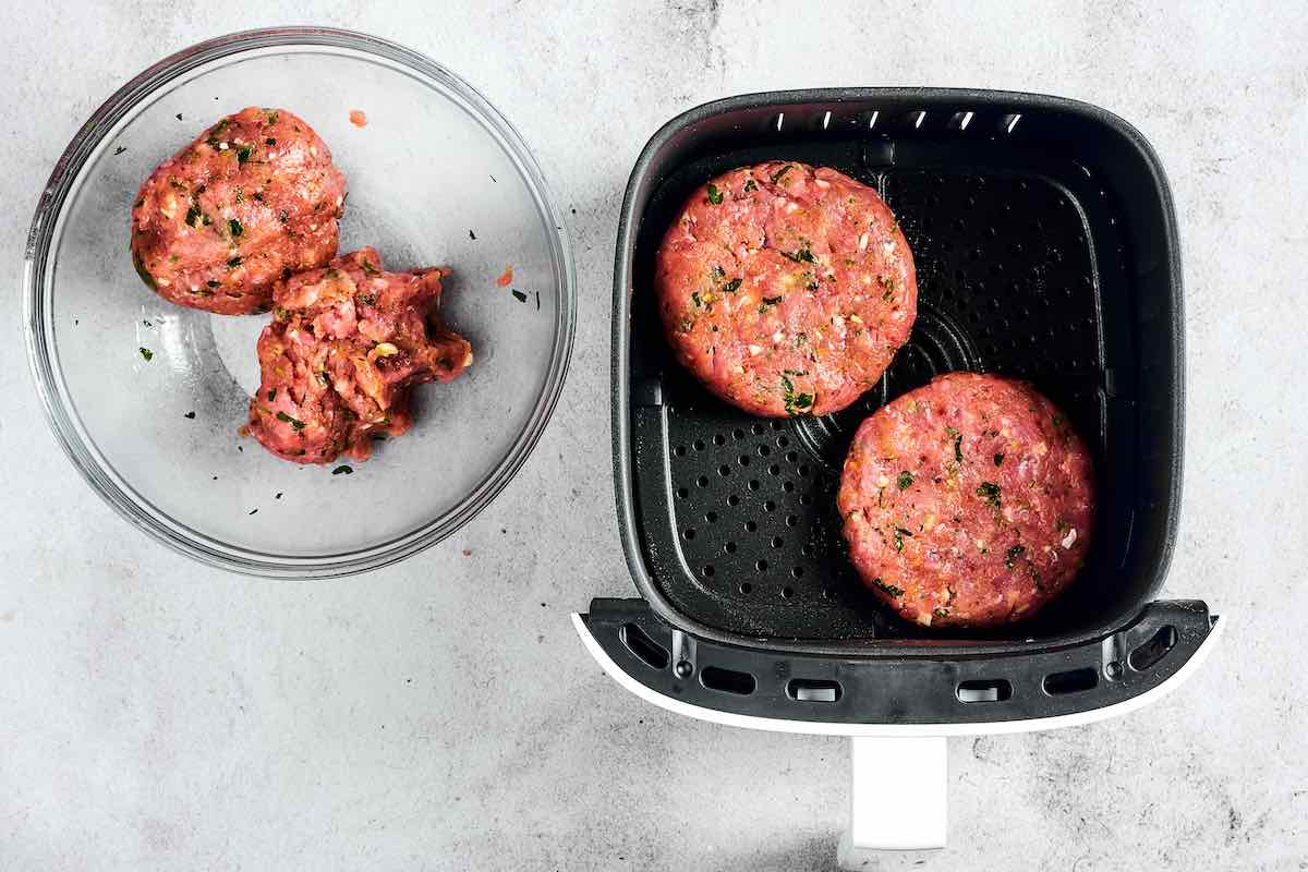 shaped raw air fryer turkey burgers in the air fryer basket.