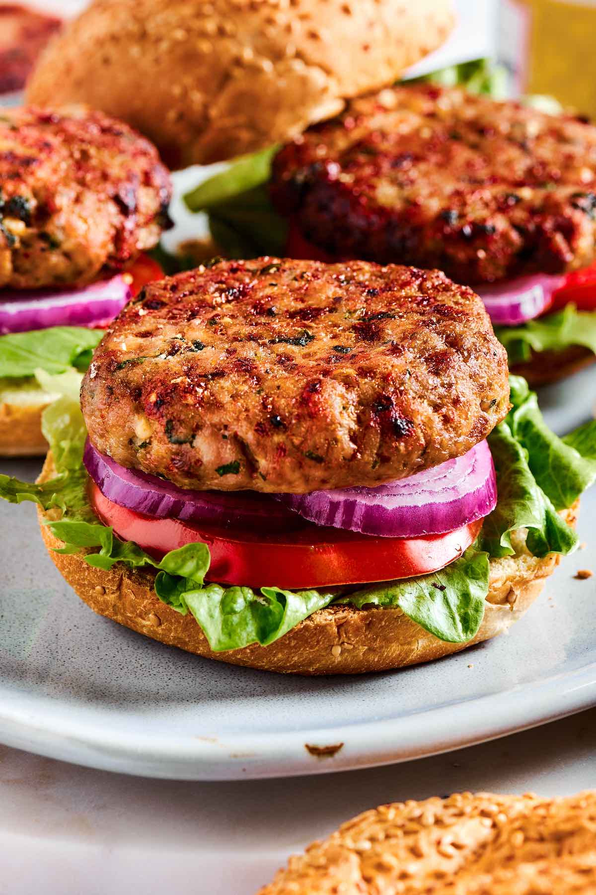 air fryer turkey burgers in a bun with onion, sliced tomato, and lettuce.