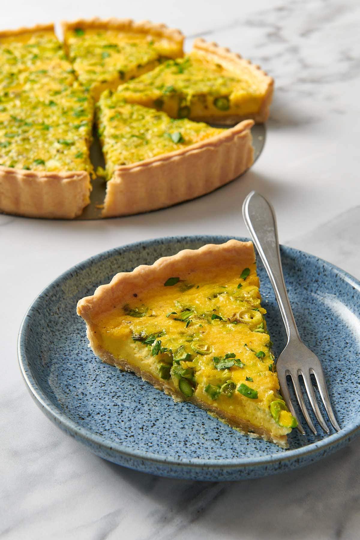 slice of asparagus quiche on a plate with a fork.