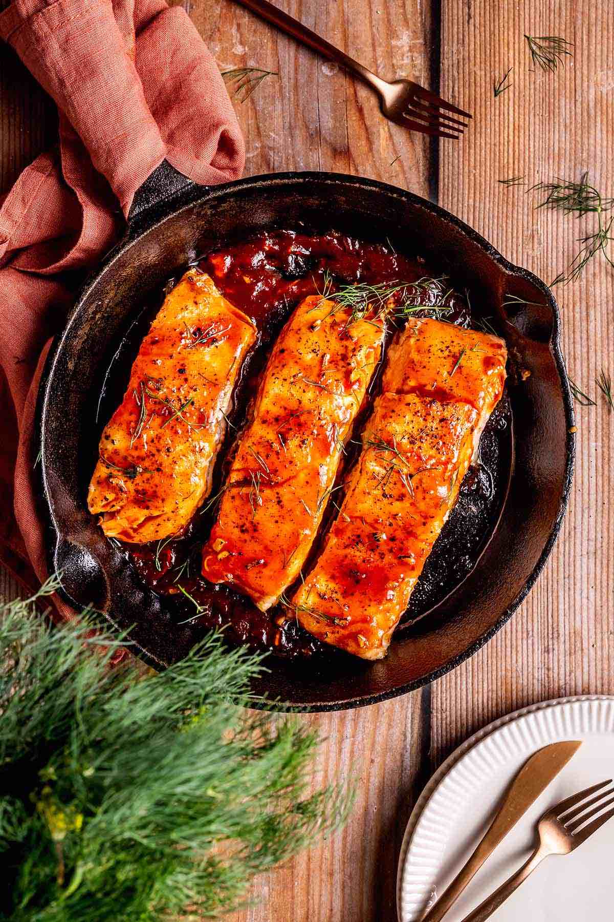 firecracker salmon in a skillet with fresh herbs.