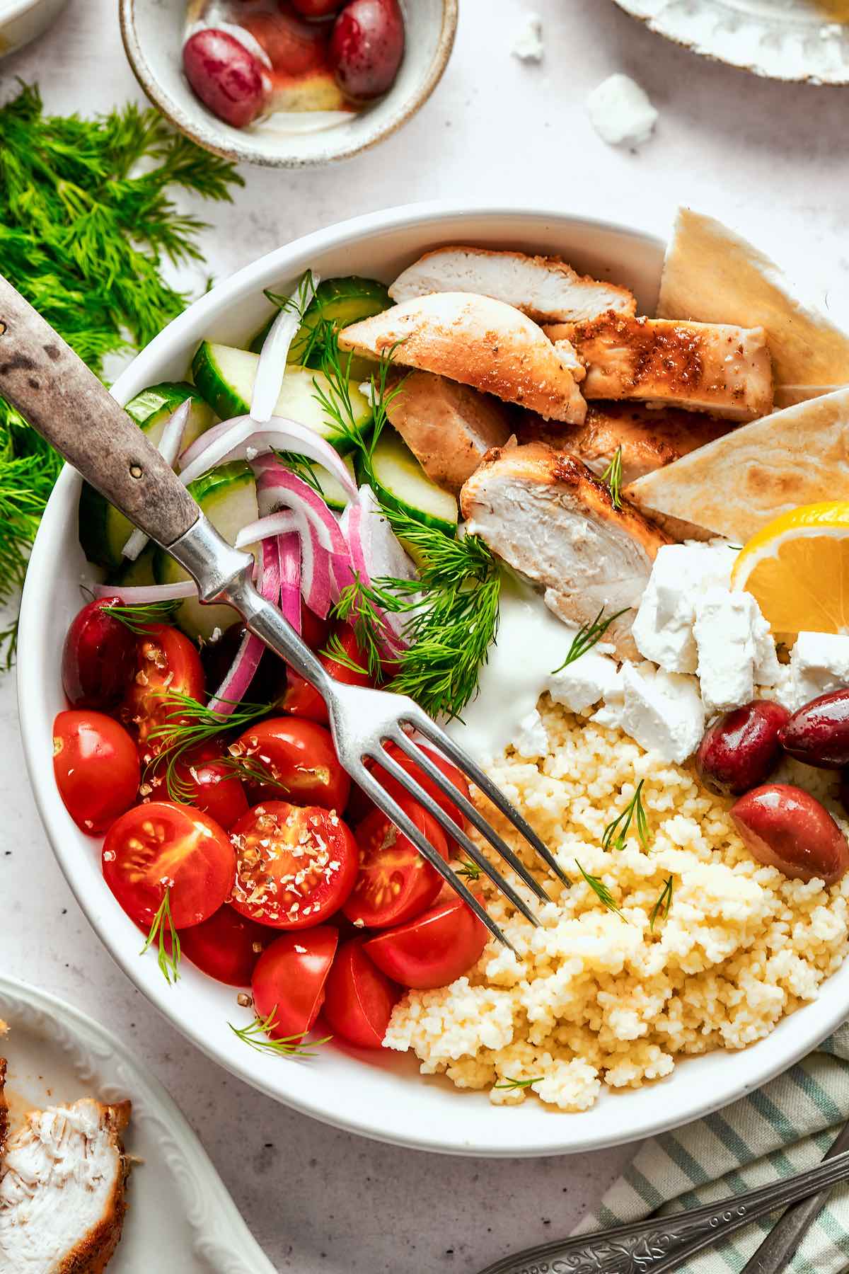 Greek bowls with grilled chicken, feta cheese, cherry tomatoes, red onion, cucumber, olives, and feta.