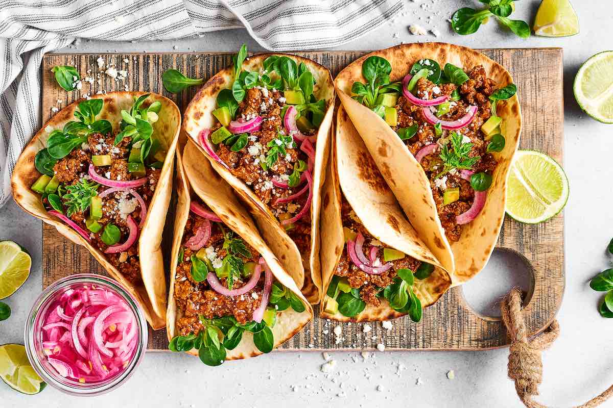 assembled ground chicken tacos on a board.