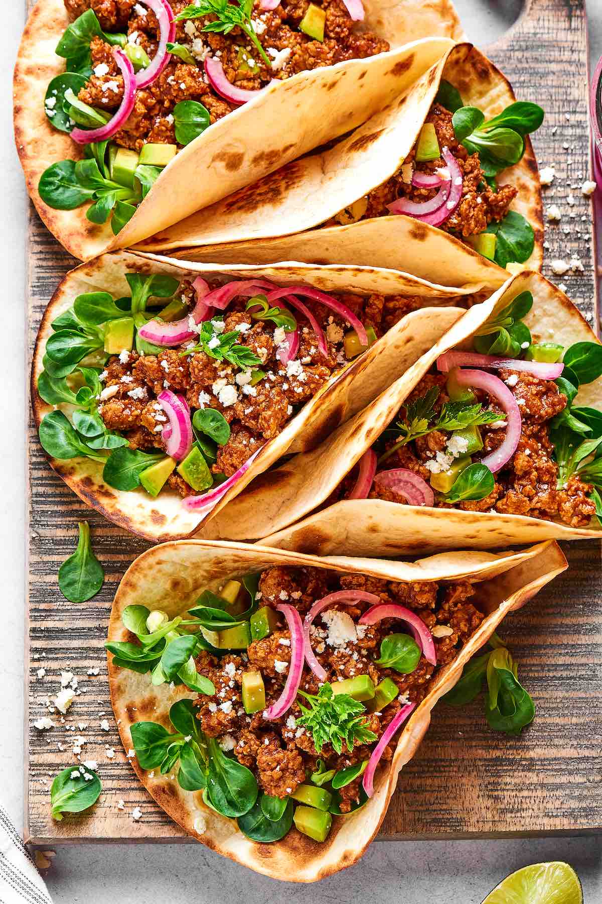 ground chicken tacos with red onions, feta cheese, and parsley.