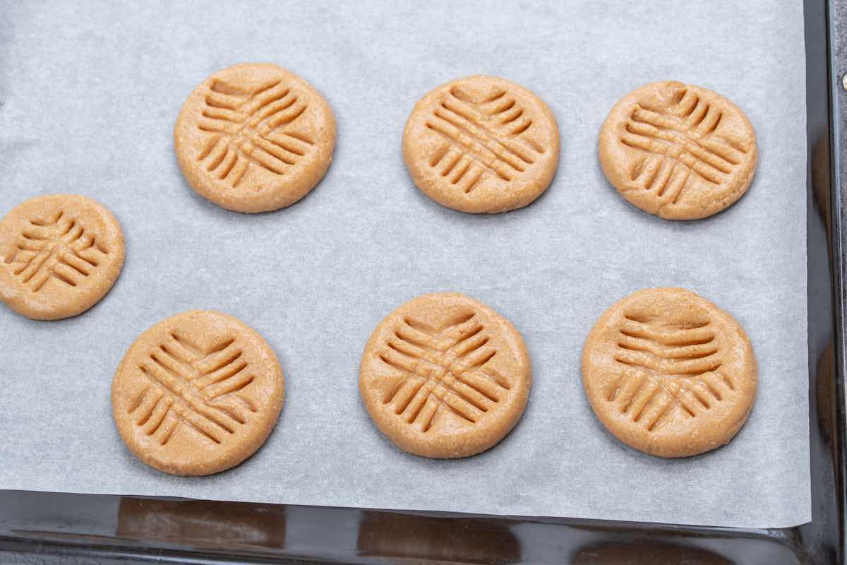 unbaked cookies on a baking sheet with a criss cross pattern.