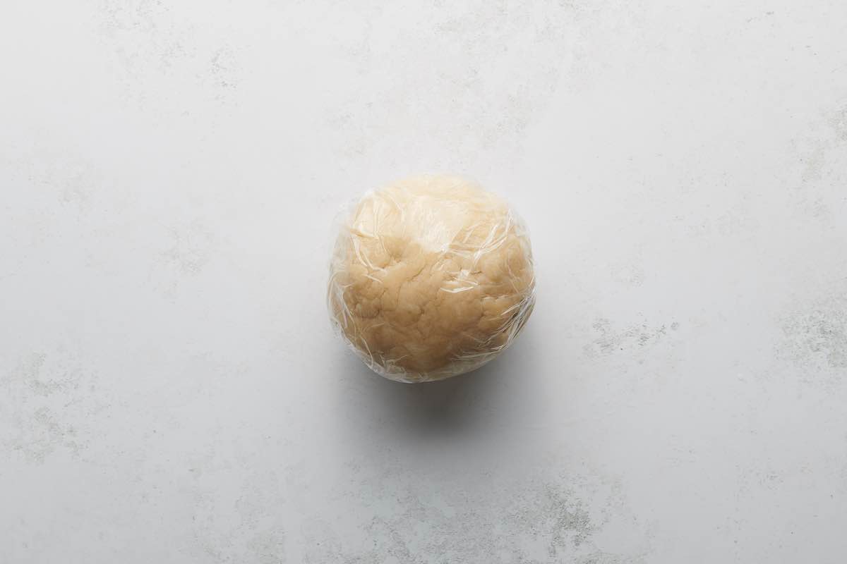 ball of pie crust covered in saran wrap.
