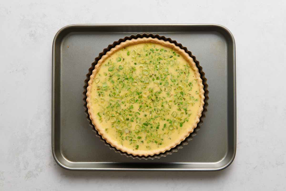 assembled asparagus quiche on a baking sheet.
