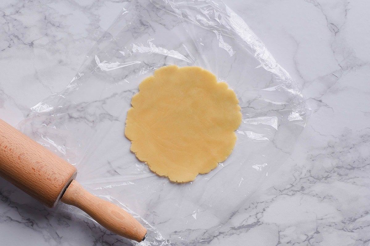 flattened dough on a kitchen bench.