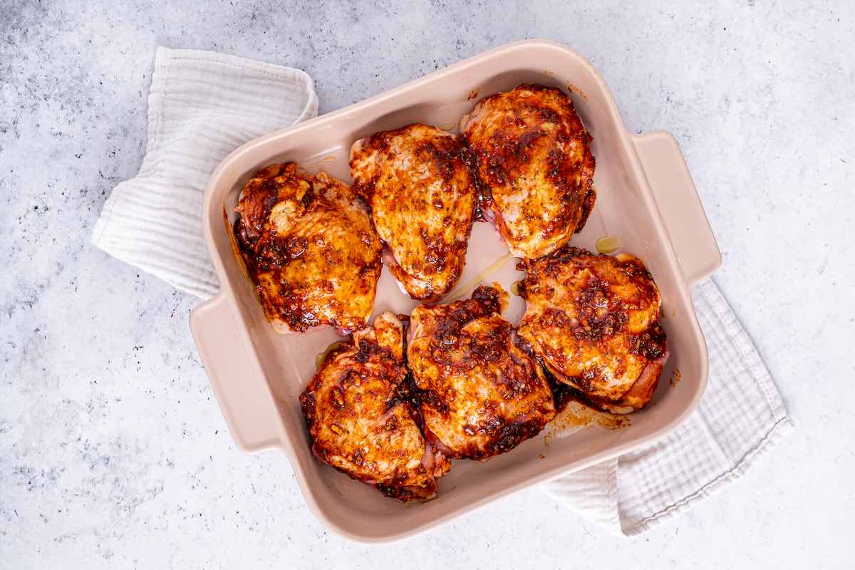 seasoned raw chicken thighs in a baking dish.