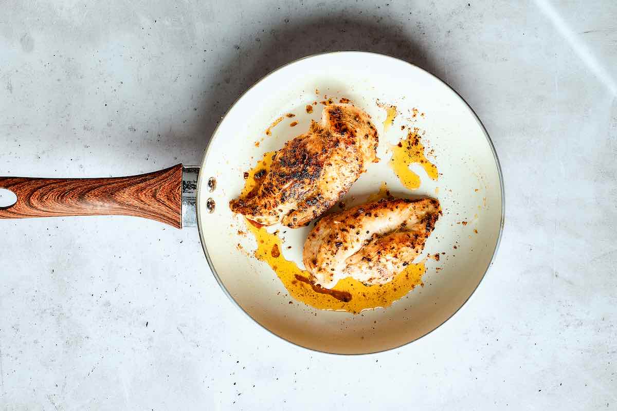 pan-frying chicken breasts in a skillet.