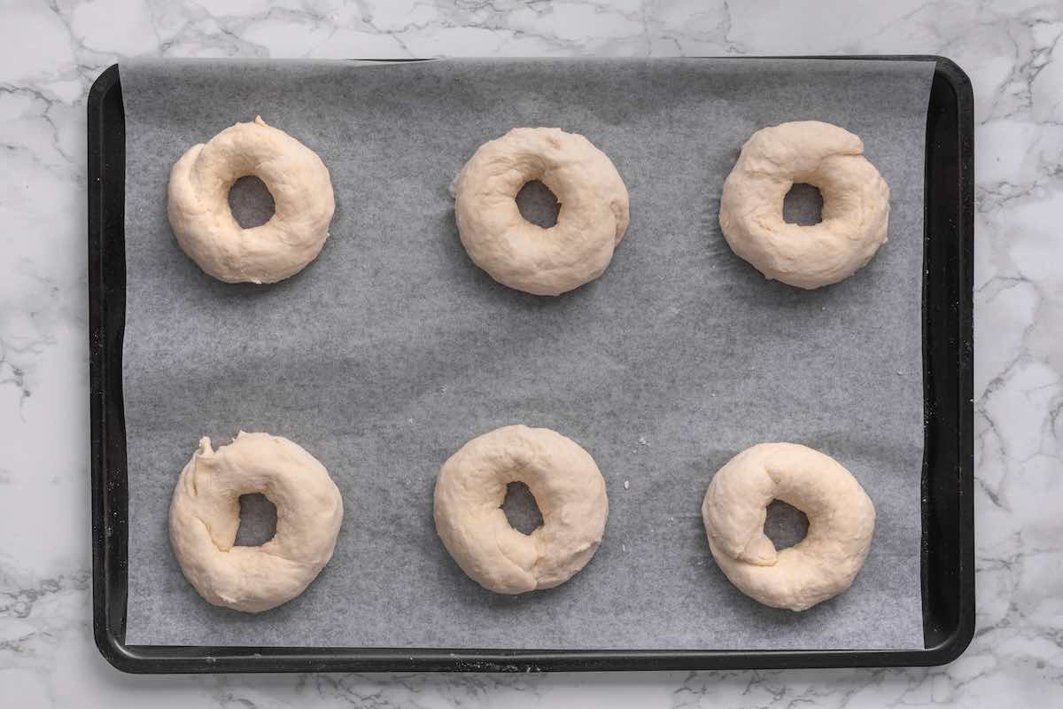 shaped bagels on a baking sheet.