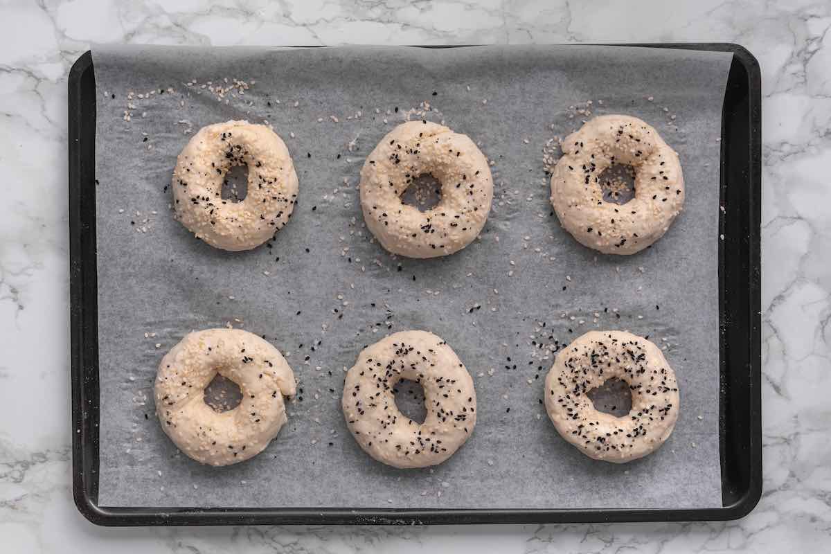 shaped bagels with egg wash and sesame seeds on top.