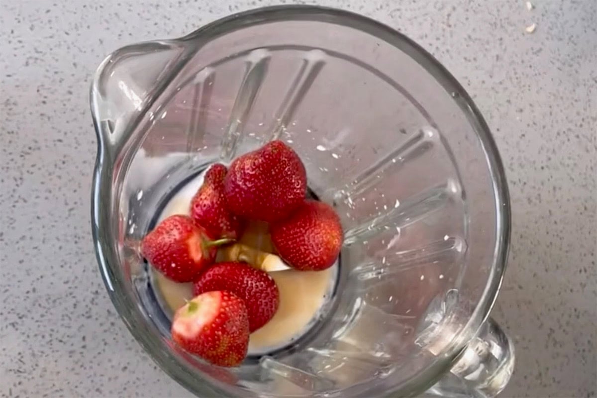 strawberries, coconut milk, and maple syrup in a blender.