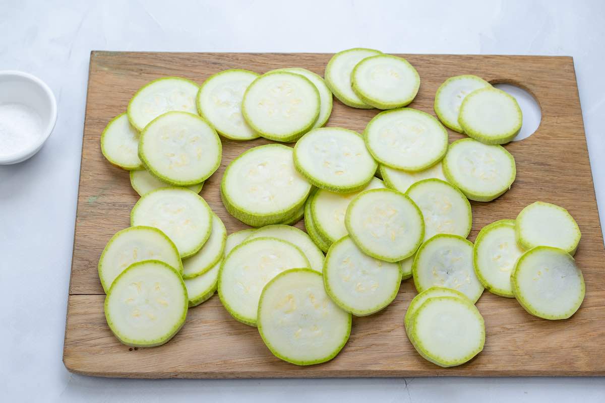 sliced zucchini medallions on a chopping board.