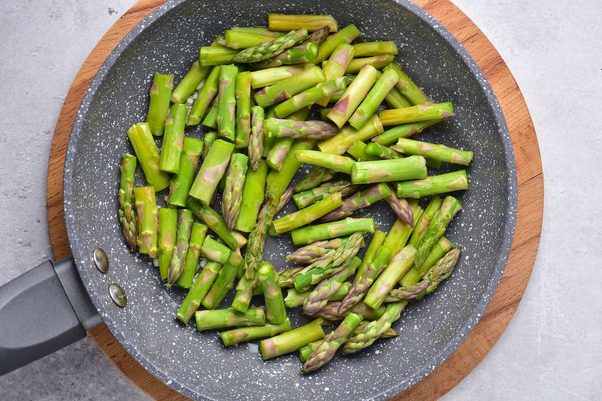 raw asparagus in a skillet with oil and butter.