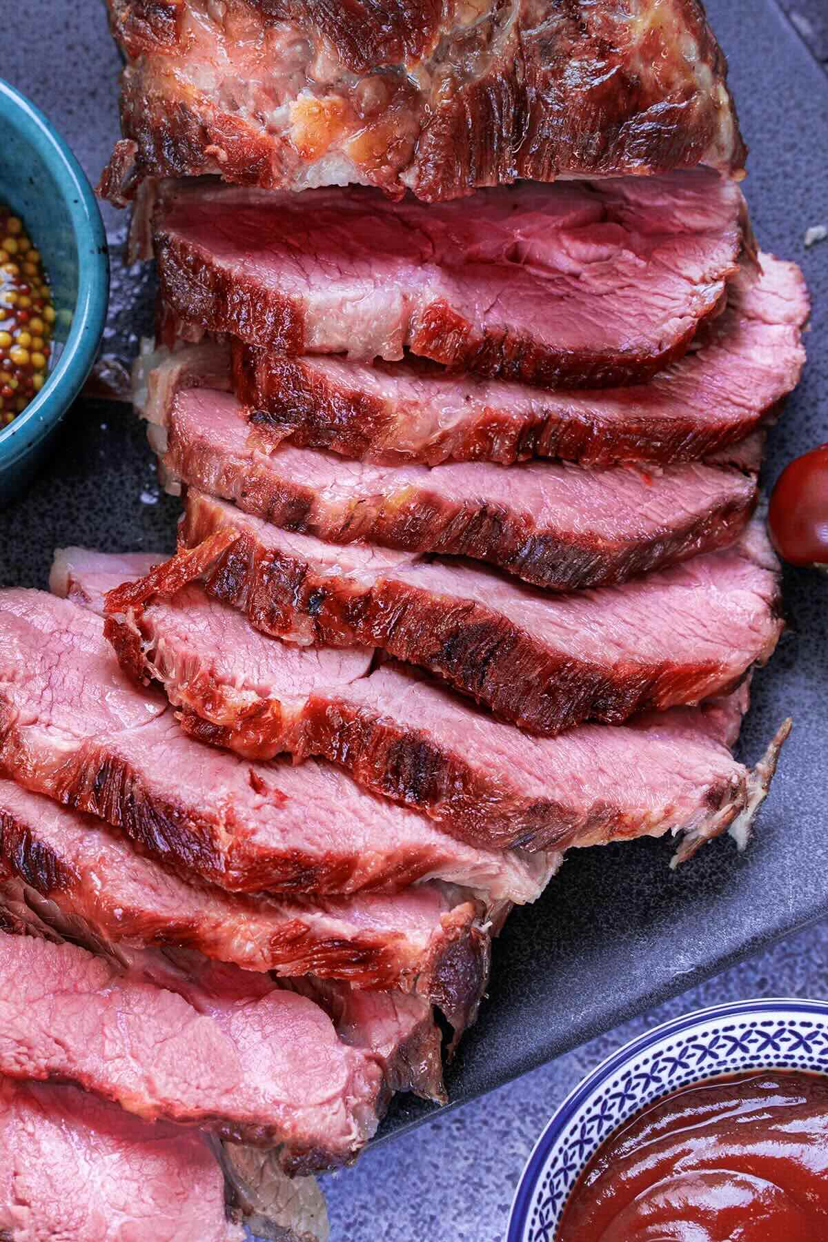 smoked corned beef sliced on a chopping board.
