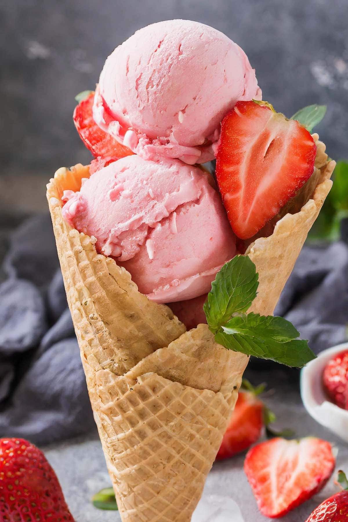 homemade strawberry ice cream in a bowl with fresh strawberries.