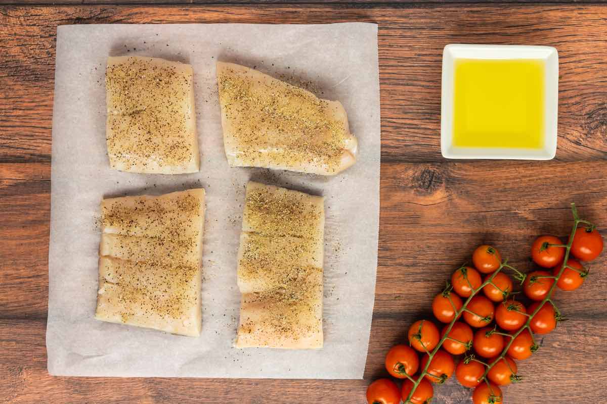 seasoned raw haddock fillets on a baking sheet.