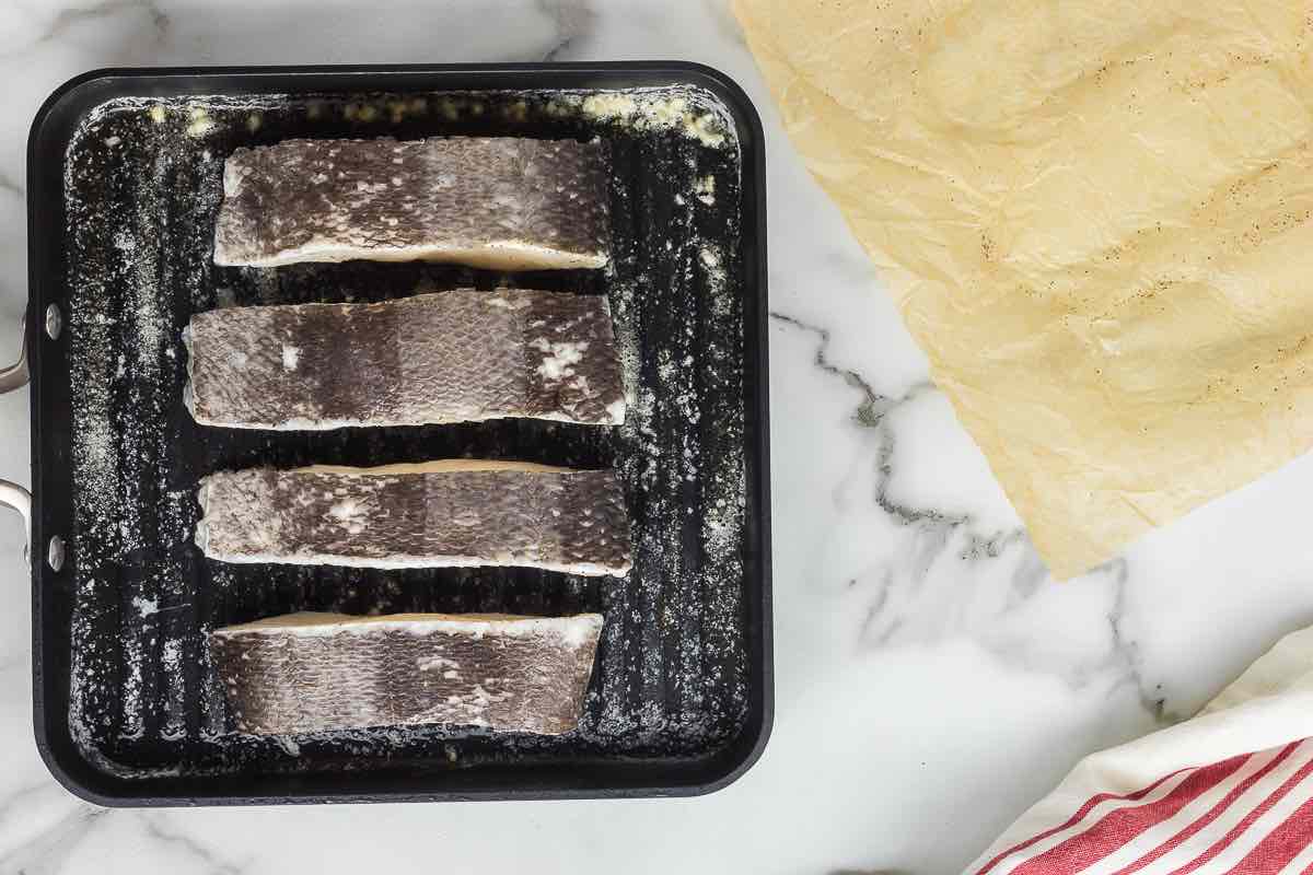 searing chilean sea bass fillets in a skillet.