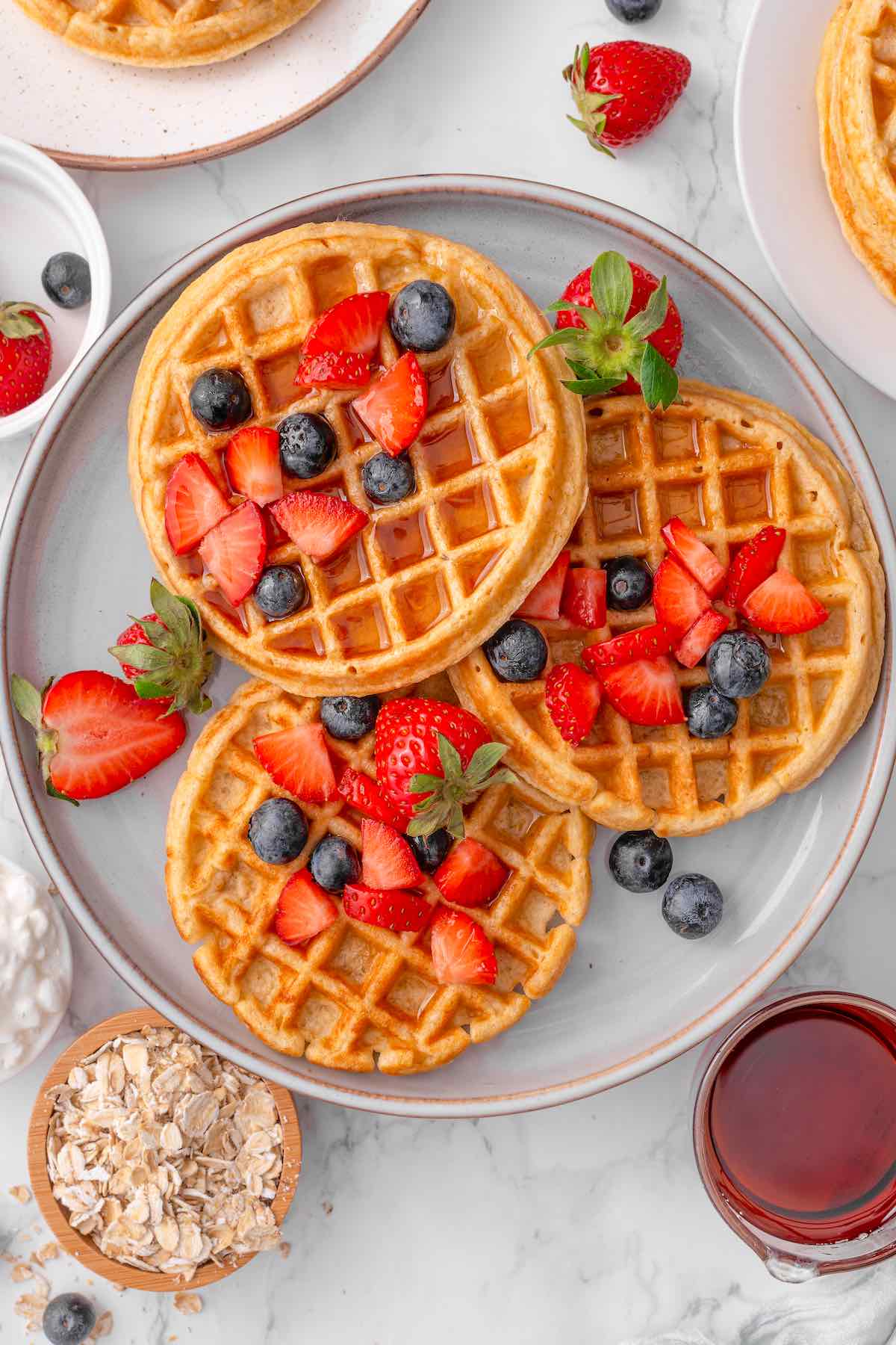 cottage cheese waffles with fresh fruit and maple syrup on top.