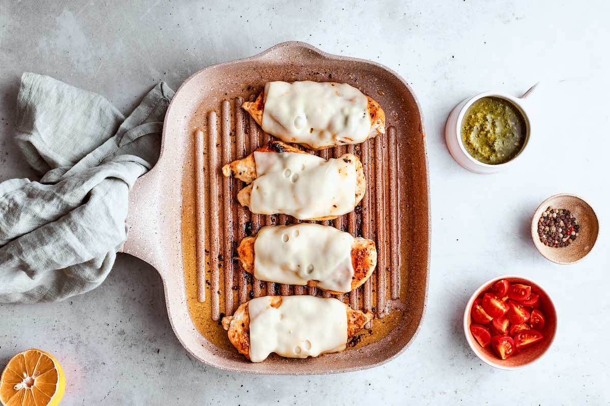 grilled chicken breasts with slices of mozzarella cheese on top.
