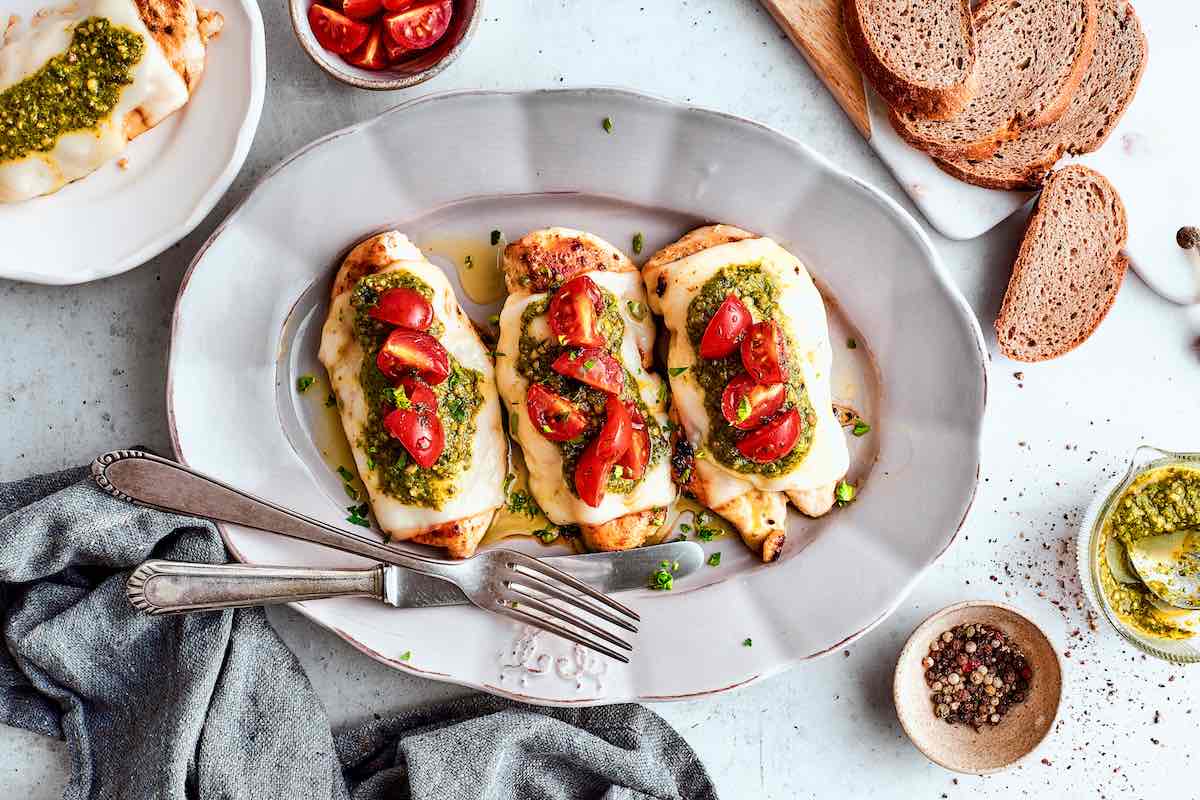grilled chicken margherita with pesto and sliced tomatoes on top.