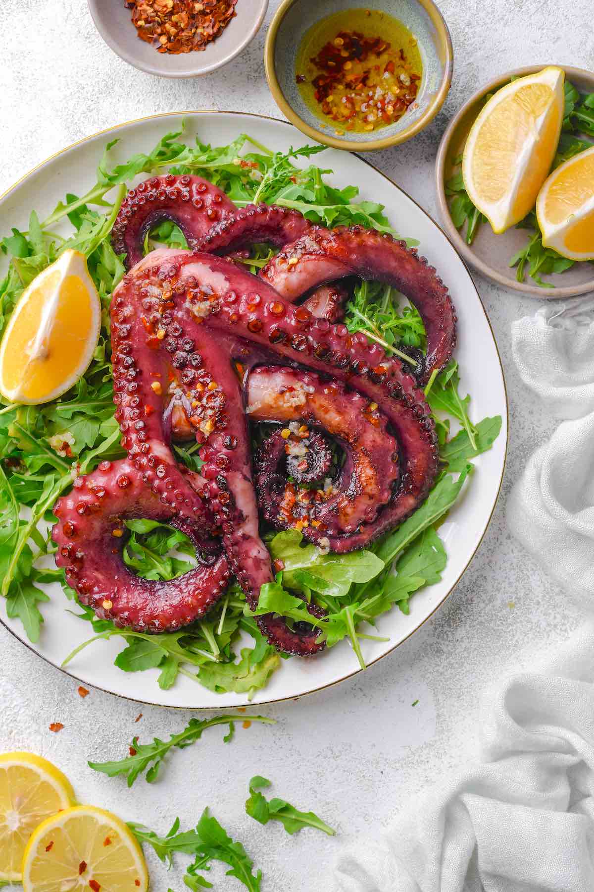 grilled octopus with fresh lemon wedges over a bed of arugula.
