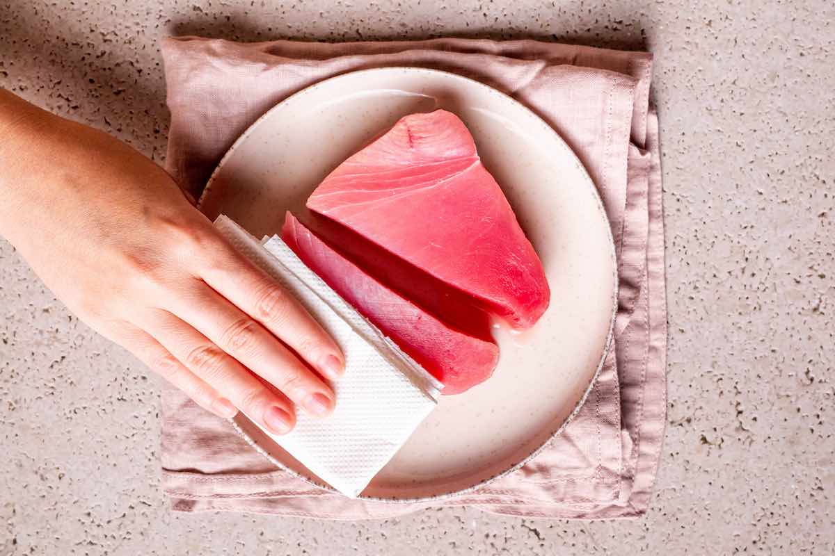 patting dry raw ahi tuna steaks.
