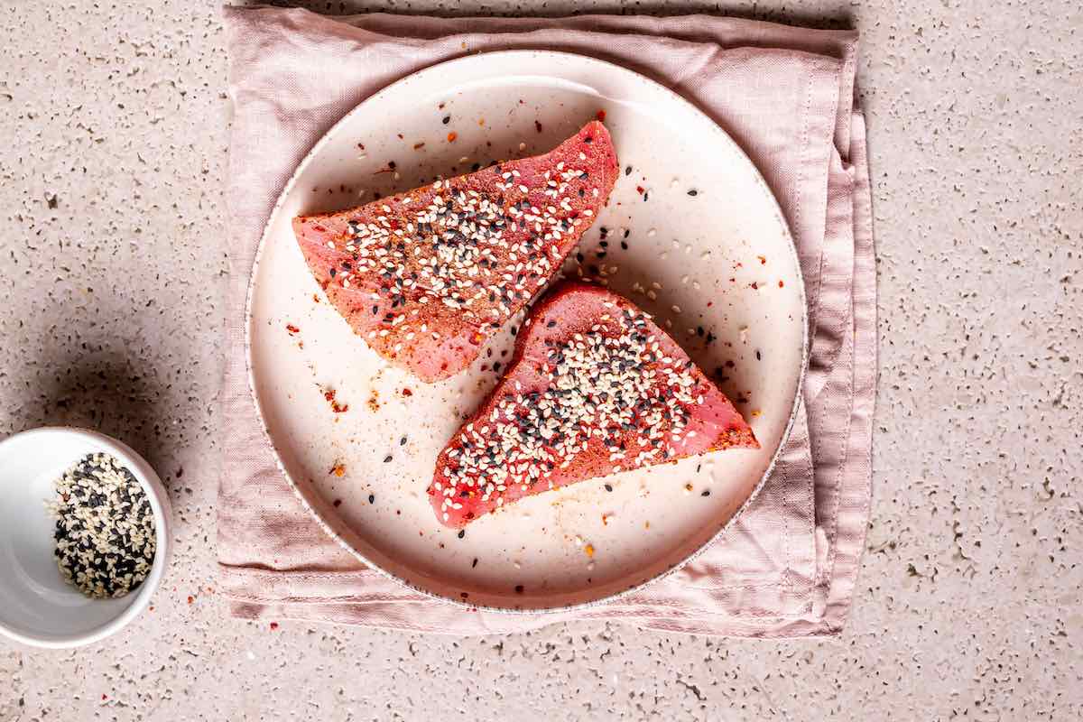 raw tuna steaks covered in sesame seeds and seasonings.