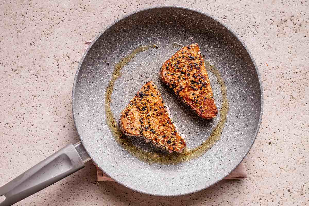 pan-searing ahi tuna steaks in a skillet.