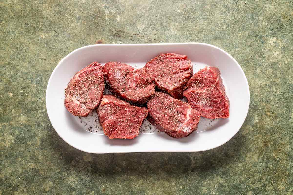 raw seasoned filet mignon on a plate.