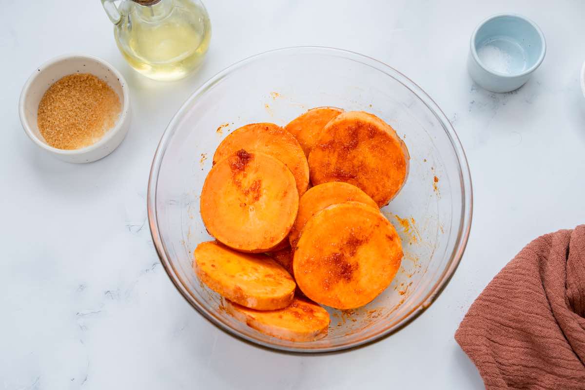seasoned raw sweet potatoes in a bowl.