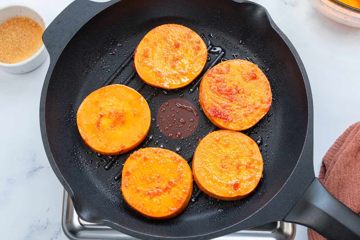 raw seasoned sweet potato rounds in a grill.
