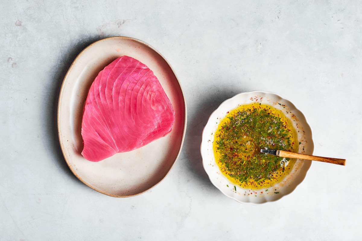 raw tuna steak with a bowl of marinade next to it.