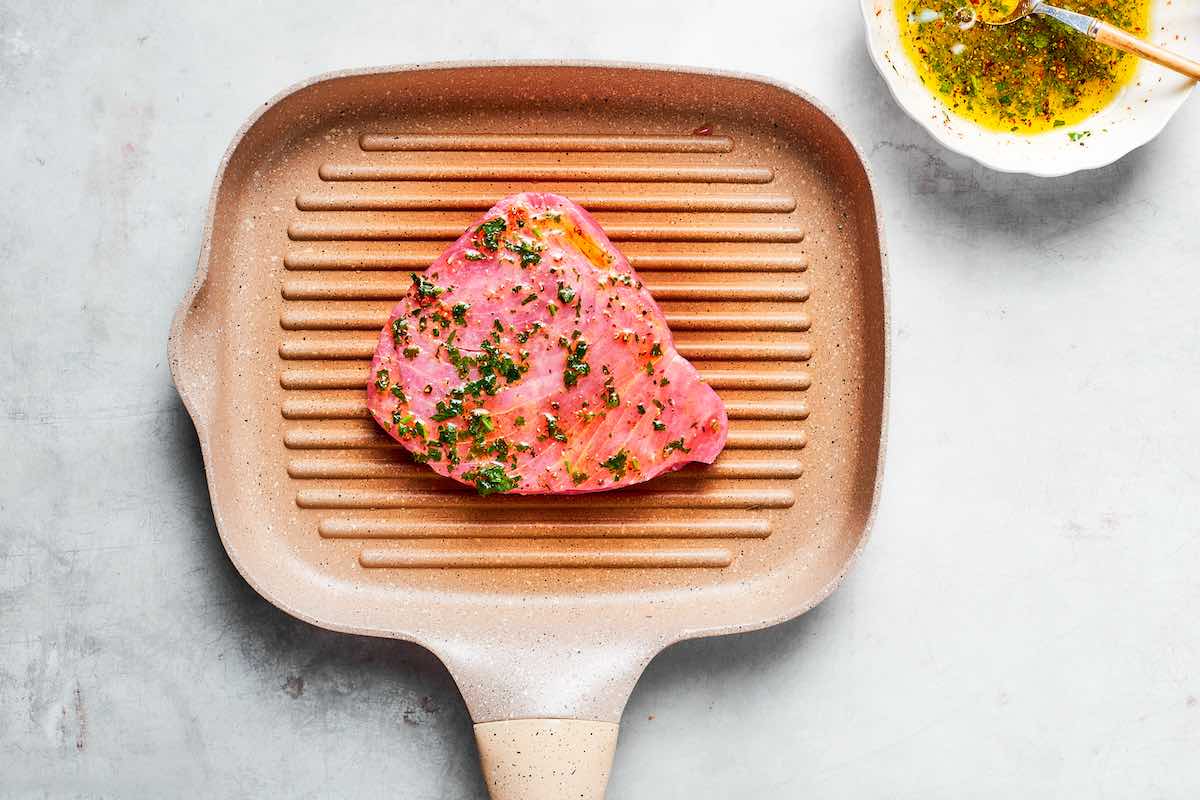 raw marinated tuna steak on the grill.