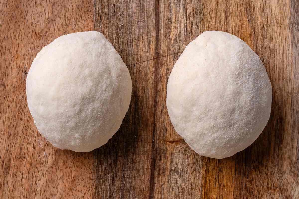 two balls of dough on a wooden board.