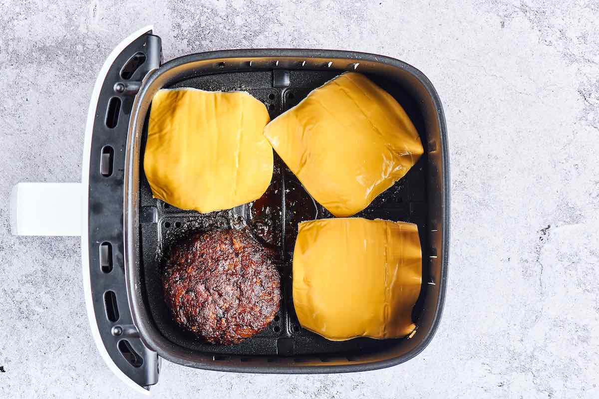burger patties with slices of cheese on top in air fryer.