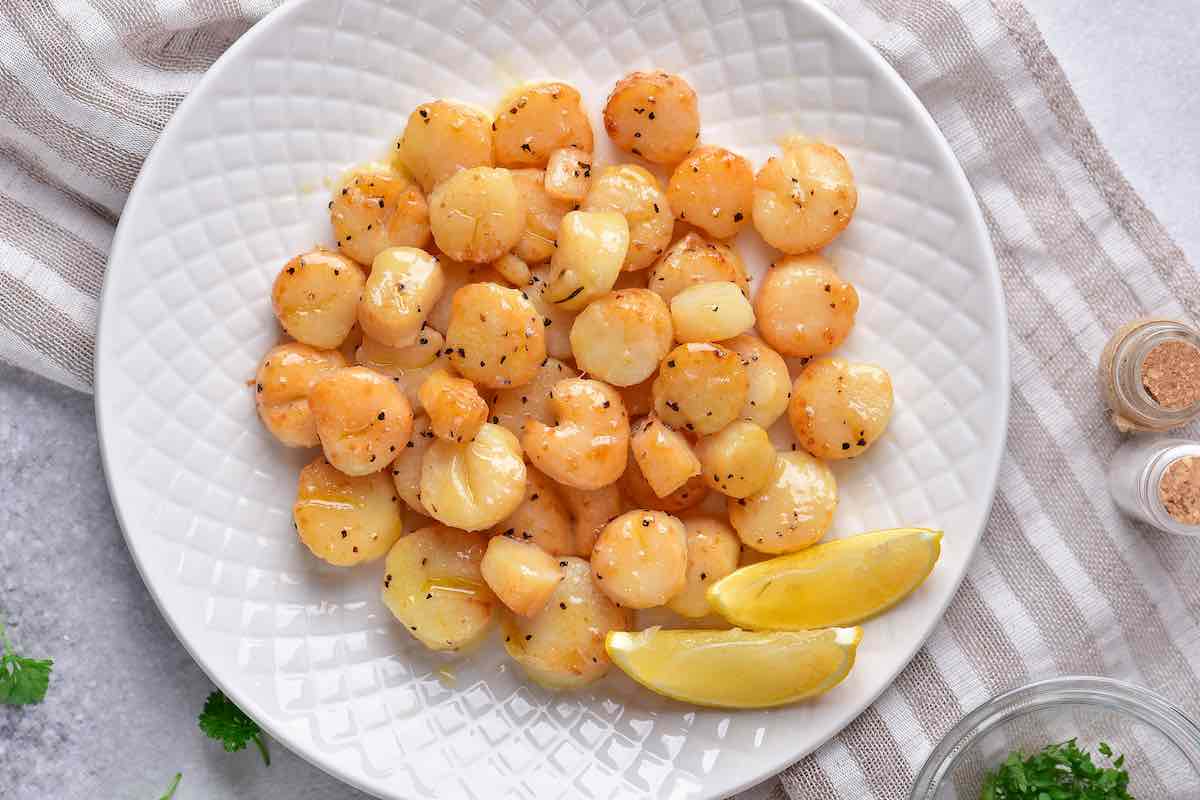 air fried scallops on a plate with fresh lemon slices.