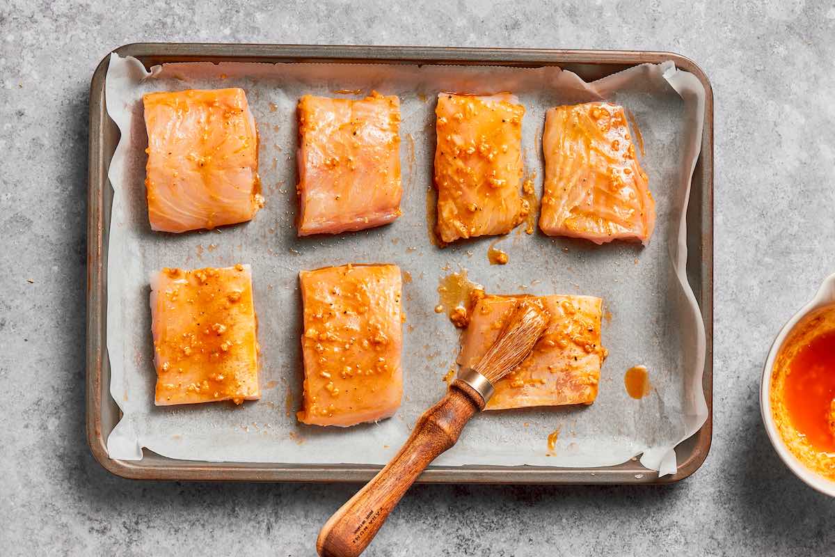 raw seasoned halibut fillets on a baking sheet.