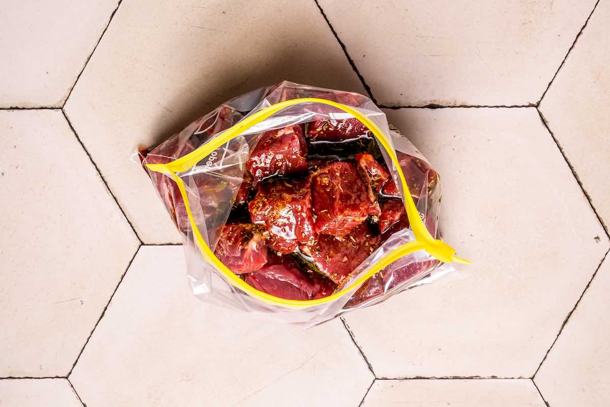 raw steak chunks in marinade in a ziplock bag.