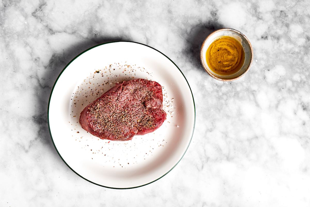 seasoned raw steak with salt and pepper.