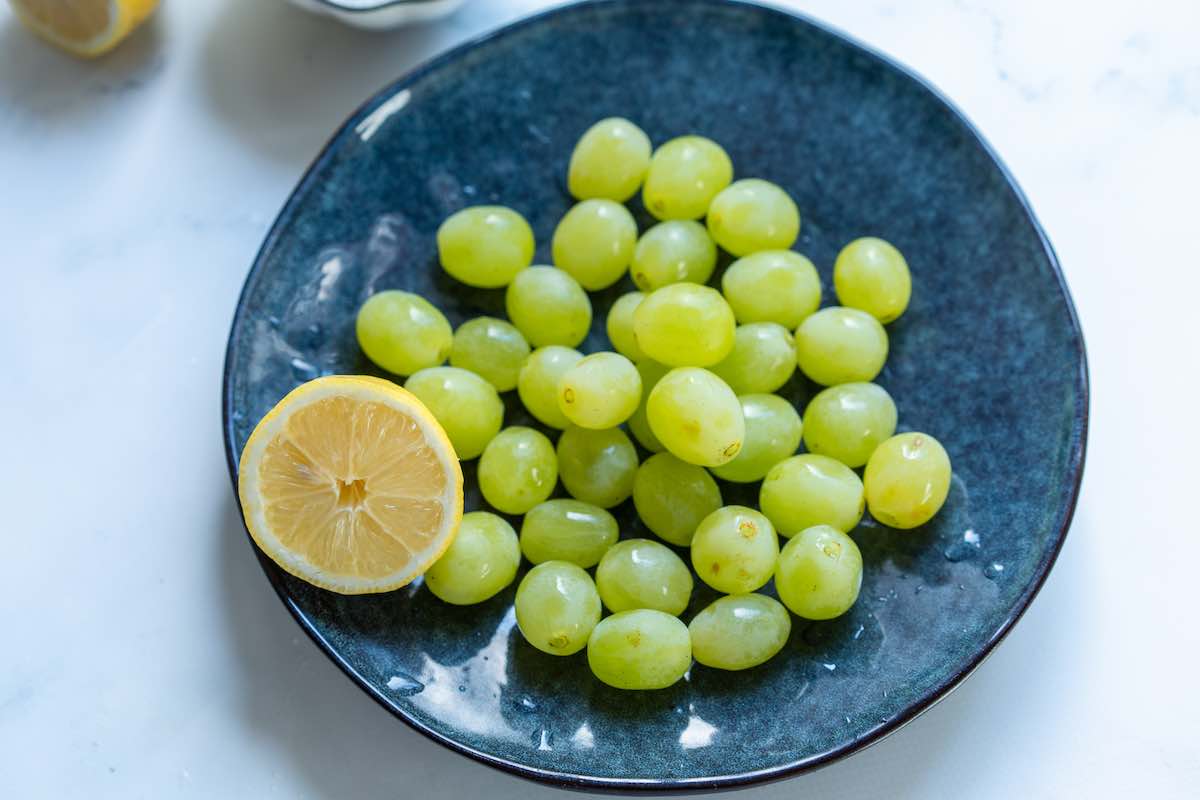 grapes in a bowl with lemon juice on top.