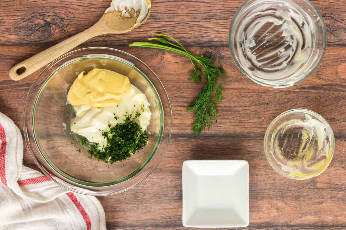 Dijon mutard, mayonnaise, herbs, and lemon juice in a bowl.
