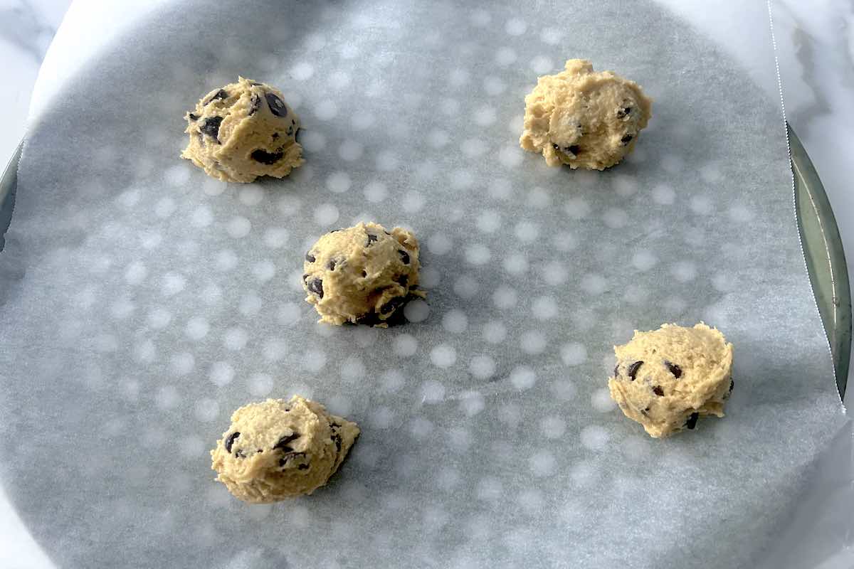 balls of eggless cookie dough on a baking sheet.