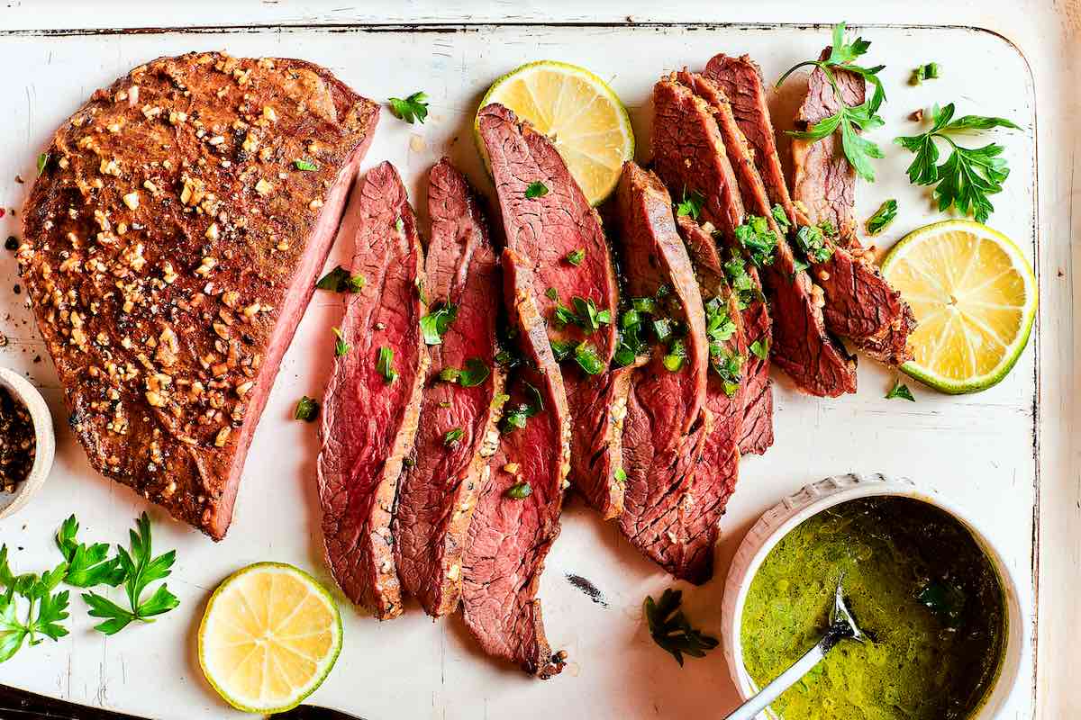 sliced cooked flat iron steak with fresh lemon slices.