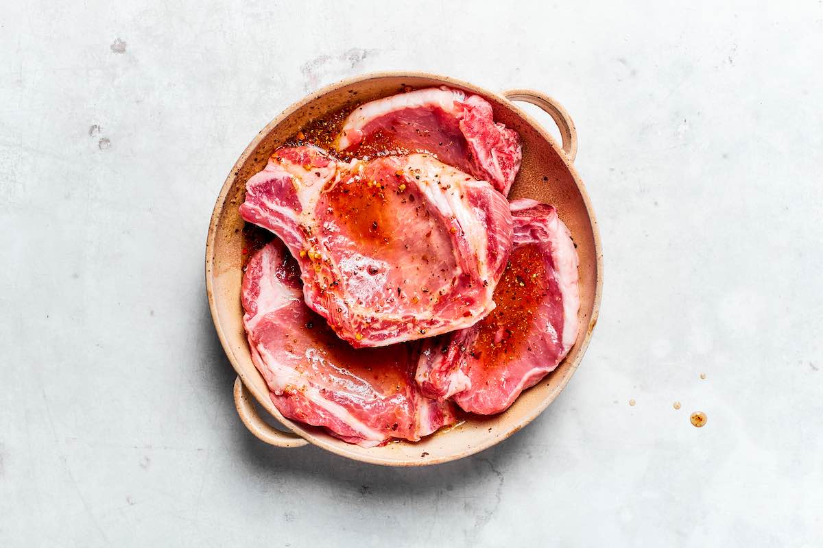 bowl of boneless pork chops with marinade on top.
