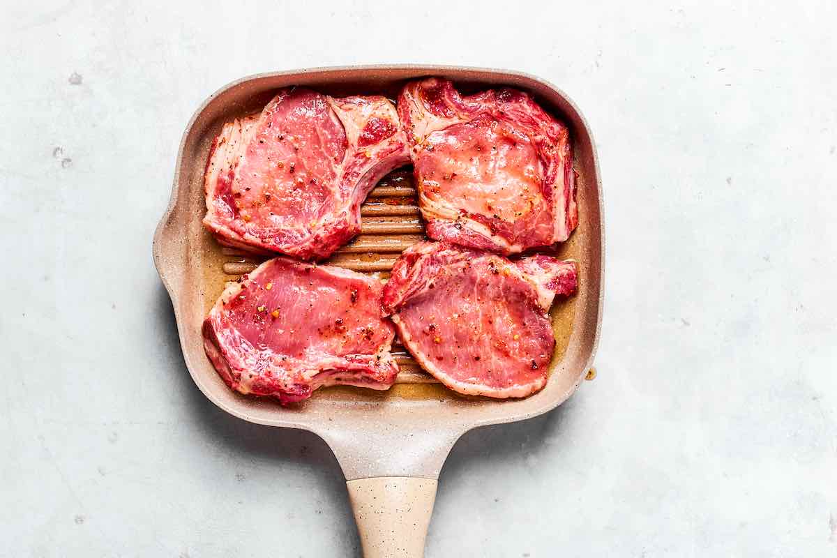 boneless pork chops grilling on a grill pan.